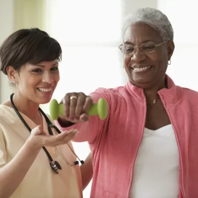 Elderly lady exercising with caregiver's assistance.