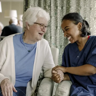 Caregiver and elderly lady sharing laughter.
