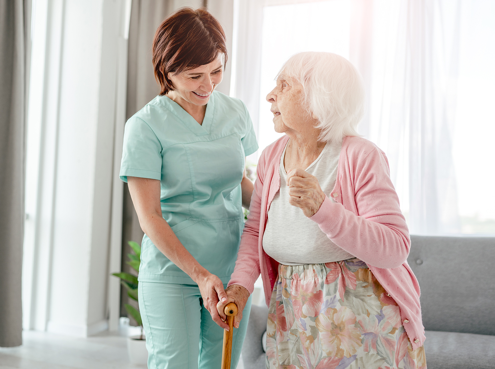 A caregiver is helping a senior woman while out on a walk.
